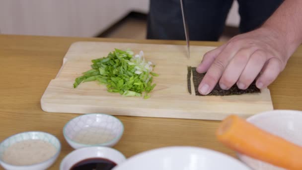 Закрыть человек режет нори сухой лист водорослей, приготовление вегетарианской японской еды — стоковое видео