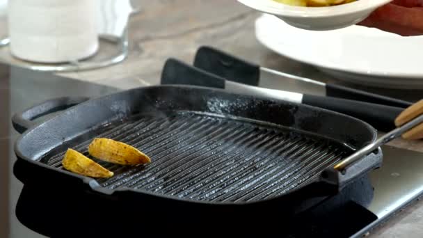 Šéfkuchař dává bramborové klíny na černou pánev. kouř stoupá z vyhřívané pánve — Stock video