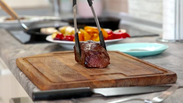 Muž doma v kuchyni krájí obrovské šťavnaté steak zblízka. Maso pečené médium — Stock video