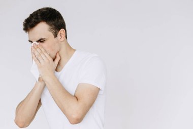 A young man sneezes into a napkin. isolated white background clipart