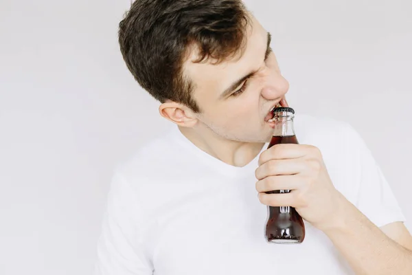 Genç bir adam dişlerini, tatlı su bir şişe açılır. izole 