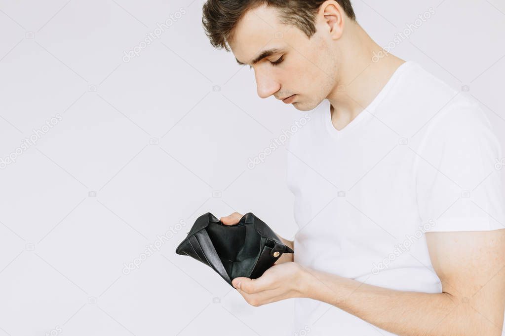 A young guy looks in an empty wallet. isolated white background