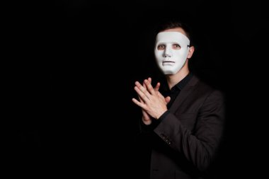 Siyah bir zemin üzerine beyaz maskeli adam. El sallar