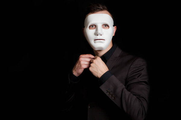 A man on a black background in a white mask. Button a button on 