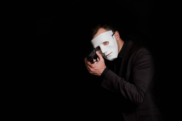 Secret agent on a black background in a white mask with a pistol