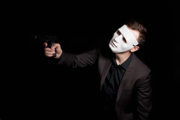 A man in a white mask on a black background, maliciously looking