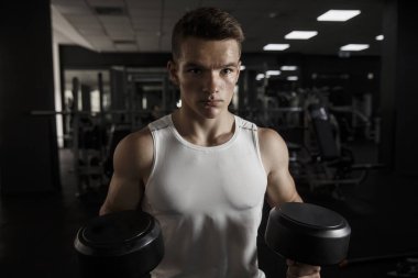 Spor salonunda dumbbells ile çalışma dışarı genç fitness adam konsantre