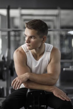 Bir adam spor salonunda oturuyor