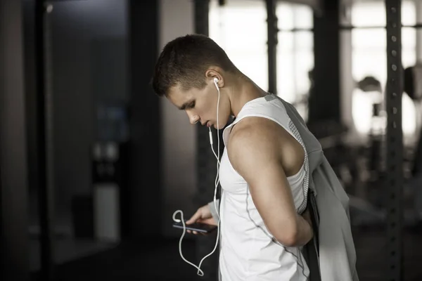 Muscular guy listening to music at the gym
