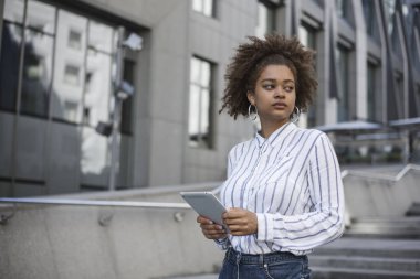 Afro Amerikan kız bir ofis binası yakınında standları ve bir tablet bilgisayar onun elinde tutan.