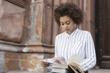 Adımlar sokakta oturan esmer kız. O bir tablet tutar ve kitap metinden yeniden yazar. Kitap kendi ayakları üzerinde yatıyordu.