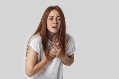 Genç bir kadın hassas bir kalbi vardır, kendini çok kötü hissediyor. Gri arka plan üzerinde izole.