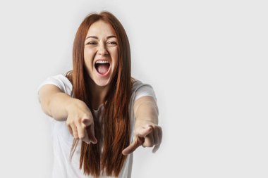 Hey siz! Kamera için gri arka plan üzerinde izole parmaklarıyla işaret eden güzel genç kadın