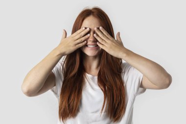 Gri arka planda beyaz t-shirt üzerinde izole kırmızı saçlı kız. O elleri ve gülümsüyor gözleri kapalı