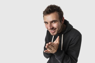 Kurnaz beyaz genç adam ellerini sinsice kamera izlerken losyonları. Beyaz arka plan üzerinde izole. Kurnaz kavramı.