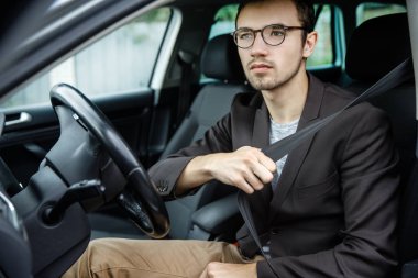 Enthusiastical genç adam kliplerinde kemerini. Arabasına oturuyor. Yol emniyet konsepti.