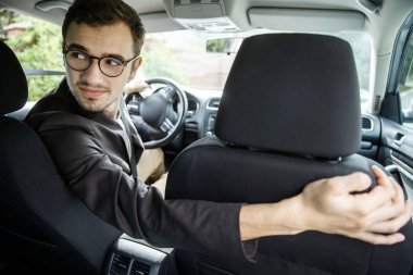 Genç sürücü görünüyor geri koltuk üzerinde taksi. Sağ elinde koltuğum. Arabasına oturuyor.