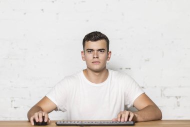 Genç bir adam masada oturan ve bilgisayarda oynamak.