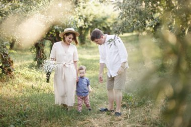 Annem ve babam bir oğulları ile bahçede yürüyüş mesafesindedir. Onlar çocuk dışında yürüyüş ve gözü üstünde. Çocuk annesine yaslanmış.