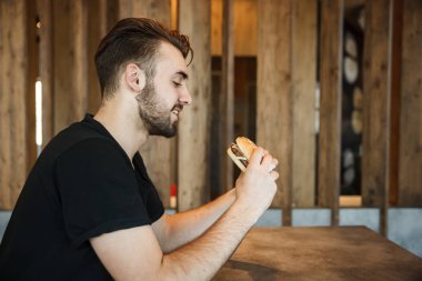 Kafede öğle yemeği. Genç bir adam burger görünüyor