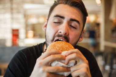Kafede öğle yemeği. Kapalı gözlerle hamburger ısırıkları.