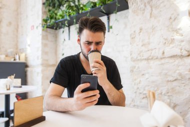 Hareket eden telefon tutarak ve kahve içme yakışıklı delikanlı