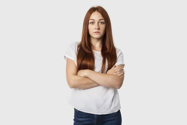 Ritratto di giovane donna europea a braccia incrociate isolata su sfondo grigio con sguardo serio — Foto Stock