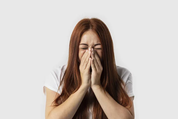 Beden dili. Gri arka plan üzerinde el ile yüz kapsayan hasta Kızıl saçlı kız hapşırma, izole