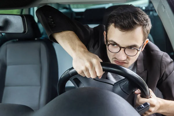 Il guidatore arrabbiato sta guardando attraverso il parabrezza. Sta guidando la sua auto e tenendo il volante con entrambe le mani . — Foto Stock