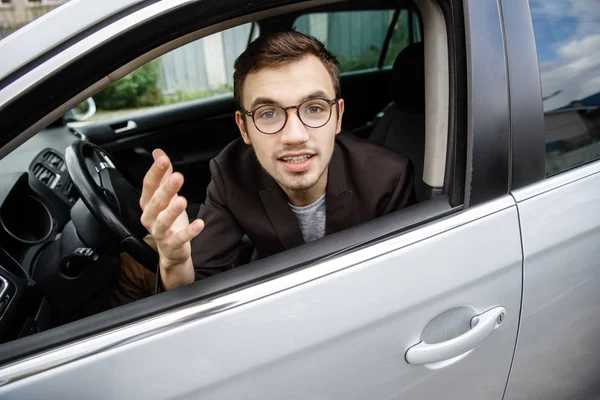 Fiatal ember nézi a kamerát, miközben ül a kocsiját. Ő elmagyarázza valamit. — Stock Fotó