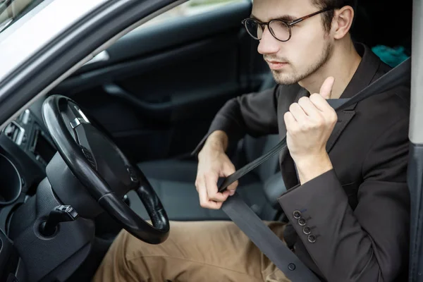 Jonge man clips op zijn riem. Hij zit op zijn auto. Concept van de veiligheid van de weg. — Stockfoto