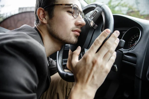 Giovane addormentato appoggia la testa sul volante. Ha le mani sul volante. Concetto sicurezza stradale . — Foto Stock