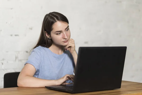 Девушка задумчиво смотрит на экран ноутбука . — стоковое фото