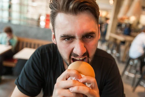 Close-up of a man eagerly eating a burger — Stock Photo, Image