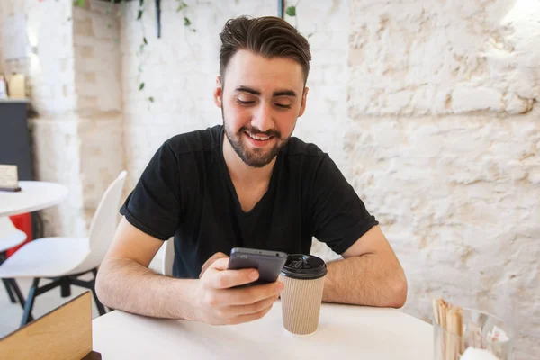 Bir adam bir kafede oturuyor ve iletileri telefonda yazar