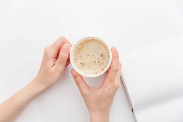 Bir kız bir fincan kahve beyaz bir arka plan üzerinde tutuyor. Beyaz