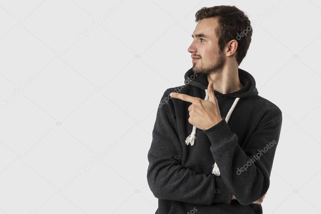 Satisfied caucasian young man pointing at blank space. Isolated on white background. Advertisement concept.