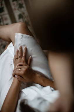 Kadın elleri onun kesişmiş bacaklar çekim üzerinde döşenmesi. Beyaz pijama giyiyor..