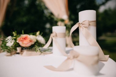 Üzerinde şeftali şeritleri olan üç beyaz mum masada duruyor..