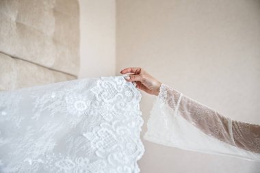 Kadın el Beyaz peçe tutuyor. Arka planda şeftali duvarı.