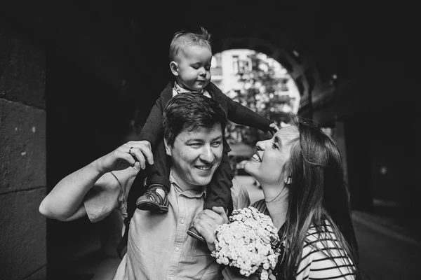 Молода сім'я сміється разом. Дитина на шиї батьків. Арковий тунель на фоні . — стокове фото