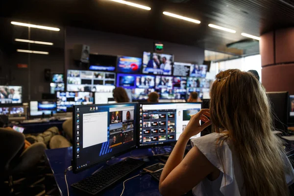 Bilgisayar üzerinde çalışan yayın yönetmeni. Arka planda büyük yayın merkezi.