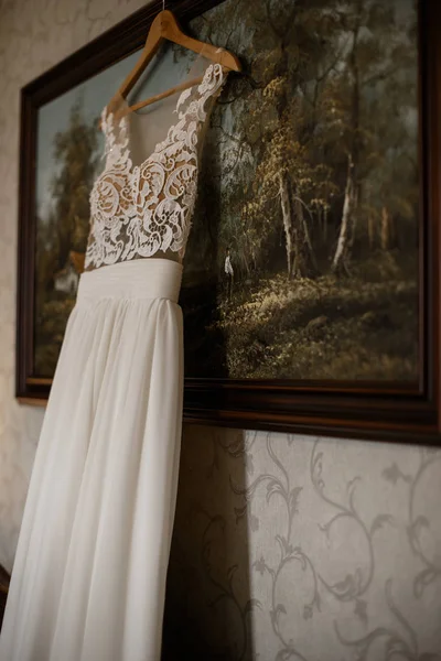 White wedding gown is hanging at the painting. Wedding preparation concept.