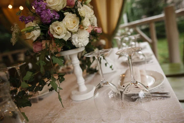 Un mazzo di fiori è in piedi sul tavolo accanto con bicchieri da vino e ricci . — Foto Stock
