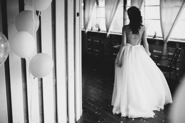 Bir gelin rahat restoranda terasında yürüyor. O beyaz bir gelinlik giyiyor.