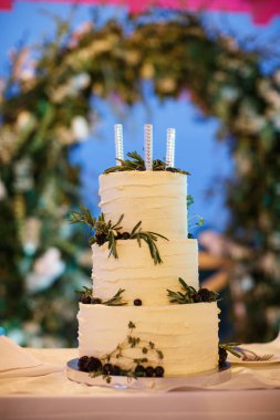 Yaban mersini, böğürtlen ve üstte üç Roma mum ile dekore edilmiş bir düğün pastası.