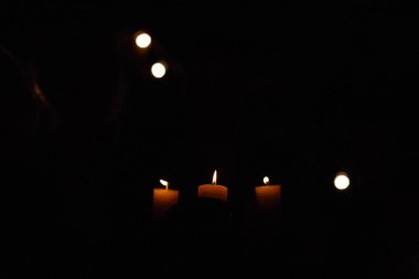 Karanlıkta duran üç yanan mum.