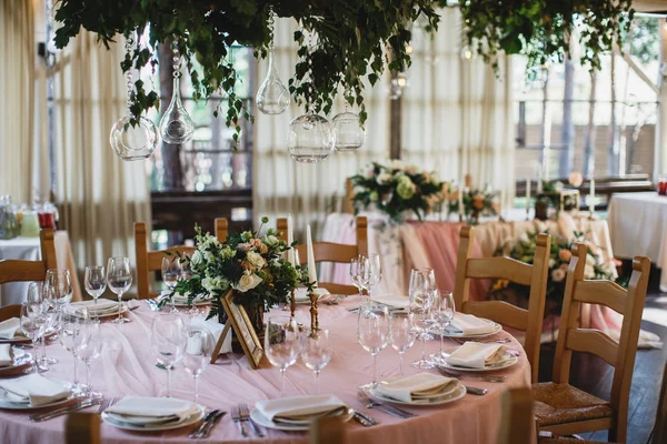 Un tavolo con tovaglia rosa, un sacco di posate e un mazzo di fiori su di esso. Restauraunt terrazza sullo sfondo . — Foto Stock