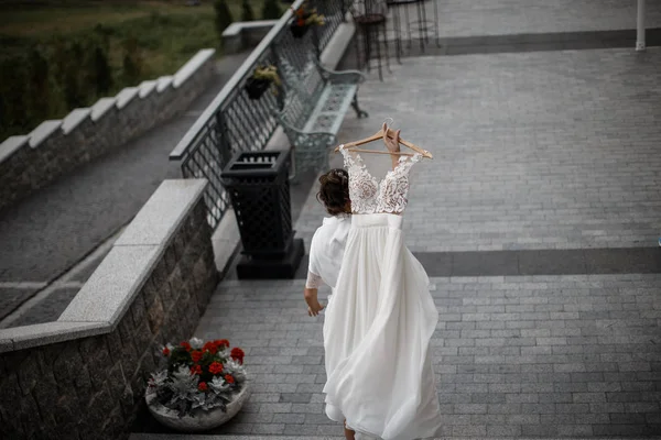 Bir kadın beyaz bir gelinlik taşıyor, Caddesi'nde yürüyor. — Stok fotoğraf
