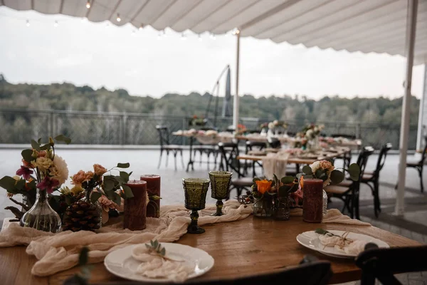 A lot of the decorations and some empty plates are standing on the table. Restauraunt terrace at the background. — Stock Photo, Image